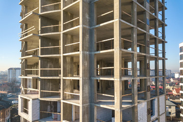 Aerial view of concrete frame of tall apartment building under construction in a city.