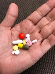 The difference kinds of tablet pills are put on the left hand for medical treatment.