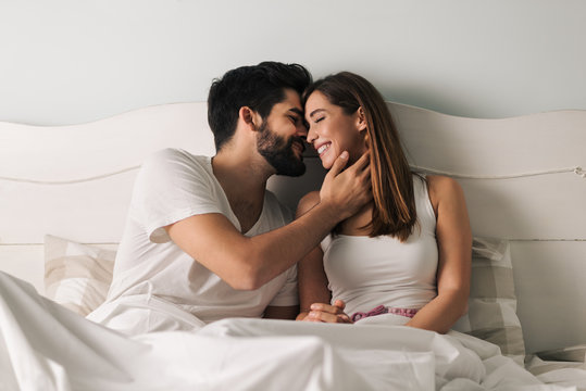 Affectionate young couple relaxing in bed and having a romantic moment