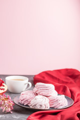 Pink pomegranate homemade zephyr or marshmallow with cup of coffee on a black and pink background. side view, selective focus, copy space.