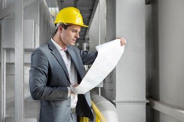 Young male architect examining blueprint in industry