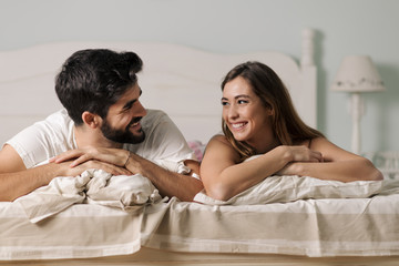 Young loving couple relaxing together on a bed and talking to each other