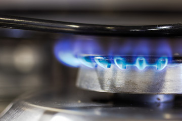 Stove flame detail lit. Closeup on blue fire in the kitchen. Cooking, preparing food.