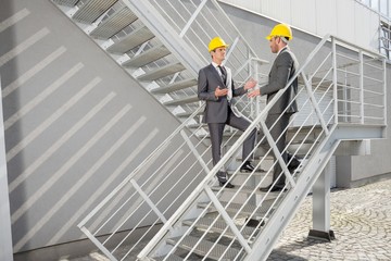 Full length of young male architects discussing on steps