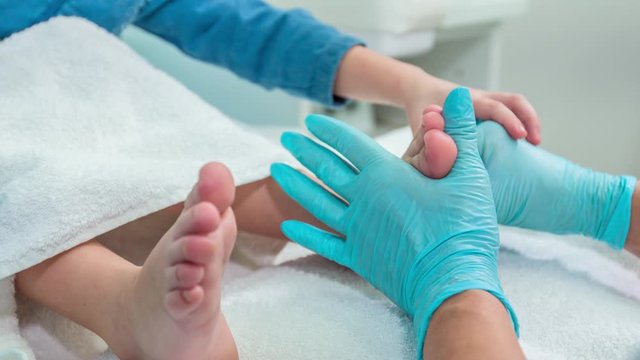 A slow-motion shot of a worker massage a client's foot.