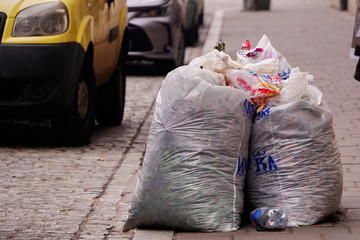 transparent bags of garbage are standing by the road or roadway, waiting for the garbage truck....