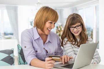 Cheerful mother and daughter shopping online at home during Christmas