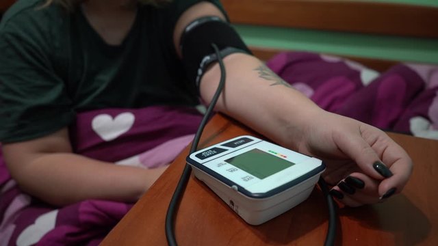 Measurement of blood pressure using a tonometer. A blood pressure monitor measures the pressure on a woman. The numbers on the tonometer display. Low blood pressure.