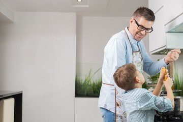 Happy father and son preparing spaghetti in kitchen