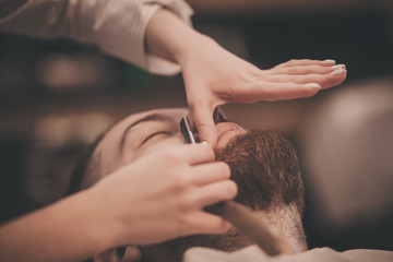 Brutal man while cutting his beard and mustache in a Barber shop