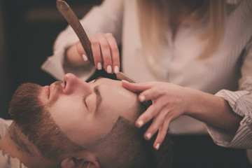 Naklejka premium Bearded man with beard getting stylish hair shaving