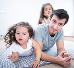 Portrait of father with daughters lying on blanket at home