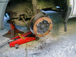 Front disc brake on car in process of new tire replacement.