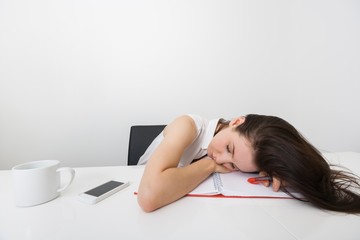 Tired businesswoman sleeping at desk in office