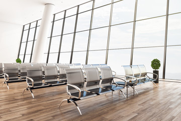 Bright airport waiting area with plant and seats.