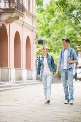 Fototapeta premium Full length of young college couple talking while walking in campus