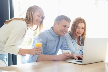 Happy parents with daughter using laptop at home