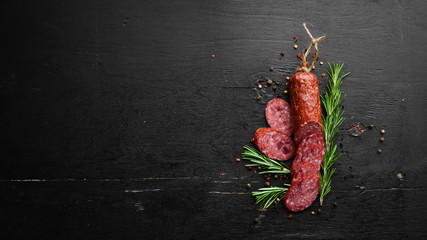 Traditional smoked salami sausage with spices. Slice sausages. Rosemary. Top view. Free space for...