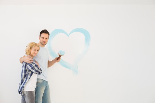Portrait of loving mid-adult couple with painted heart on wall - Powered by Adobe