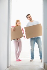 Fototapeta na wymiar Full-length of couple with cardboard boxes standing in front of entrance
