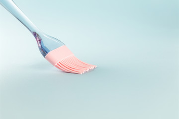 Pink silicone brush on light blue background, close up, copy space