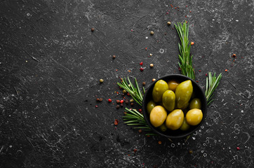 Pickled olives in a black bowl. Top view. Free space for your text.