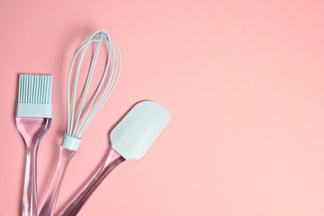  Blue silicone whisk, spatula and brush on light pink background with copy space  top view