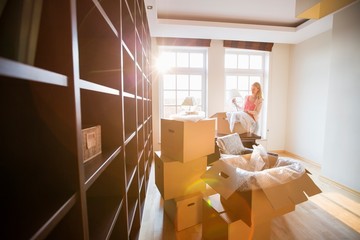 Woman unpacking lamp from moving box at new house