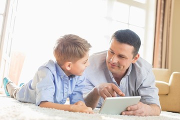 Father and son using digital table on floor at home