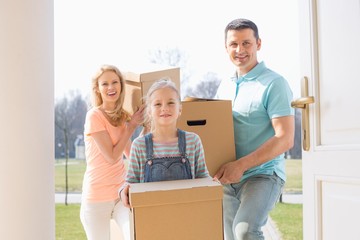 Fototapeta na wymiar Happy family with cardboard boxes entering new home