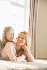 Happy mother and daughter lying on floor at home