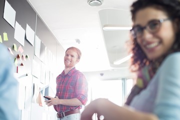 Fototapeta premium Smiling businessman with female colleague in foreground at creative office