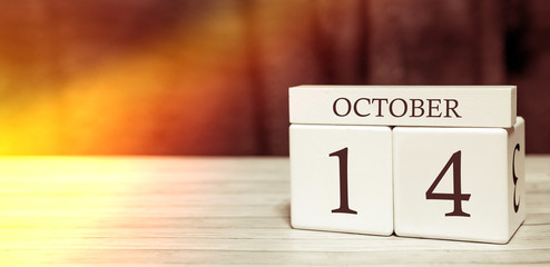 Calendar reminder event concept. Wooden cubes with numbers and month on October 14 with sunlight.