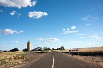 Road leading toward silos and railway crossing
