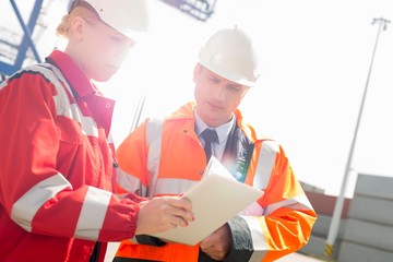 Workers discussing over tablet computer in shipping yard