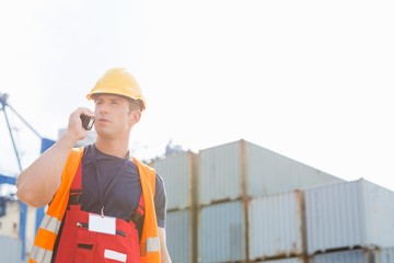 Male worker using walkie-talkie in shipping yard