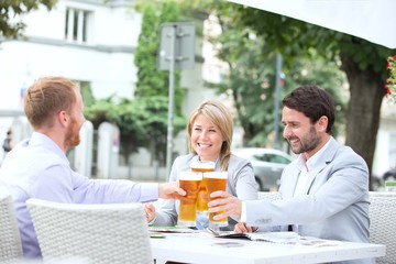 Fototapeta na wymiar Happy businesspeople toasting beer glasses at outdoor restaurant