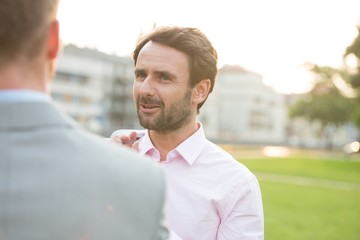 Businessman conversing with colleague at park on sunny day