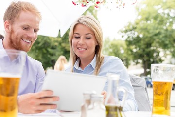 Happy businesspeople using digital tablet at sidewalk cafe