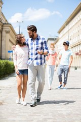 Couple walking on street with friends in background