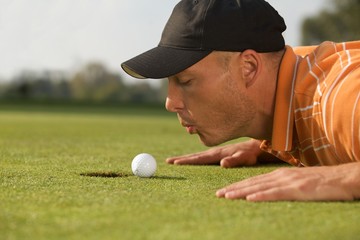 Close-up of man blowing on golf ball