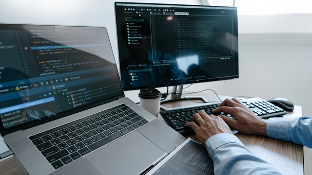 Programmer working On Computer In IT Office Typing Data Coding in software and checking code on computer screen.