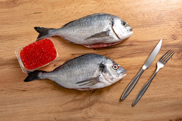 Raw dorado or sea bream fish with lemon slices. Fresh sea fish. Dorado, herbs and spices. Menu photo