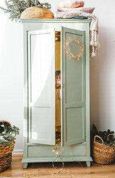 Little Girl Hiding Inside White Wardrobe.