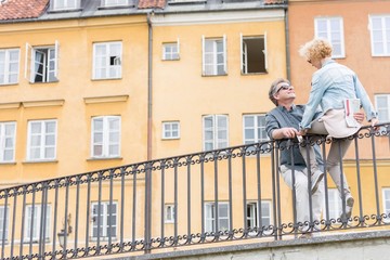 Fototapeta na wymiar Low angle view of loving middle-aged couple by railing against building