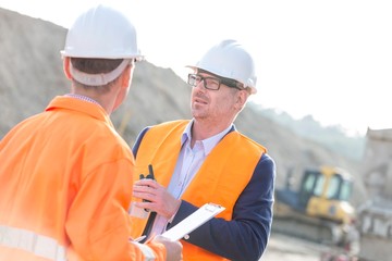 Architects discussing at construction site on sunny day