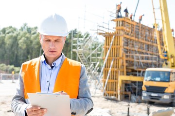 Supervisor writing on clipboard at construction site