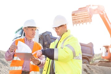 Engineers discussing over documents at construction site