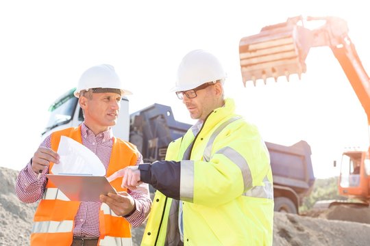 Engineers discussing over documents at construction site