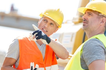 Supervisor showing something to colleague at construction site on sunny day